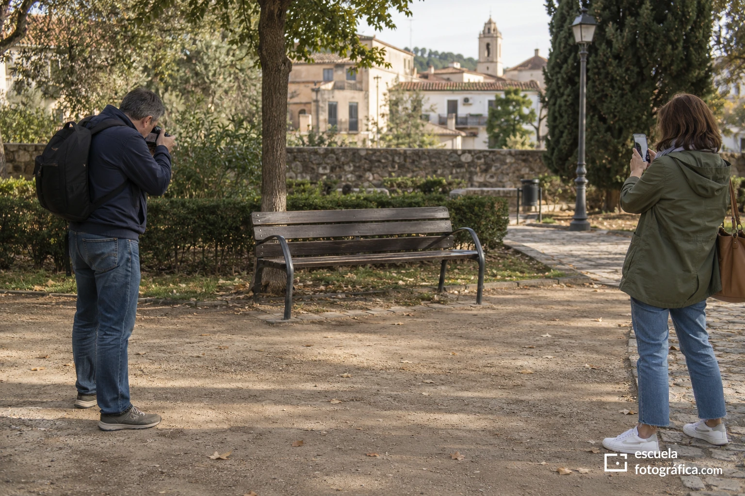 Dos personas observando un banco vacío desde posiciones diferentes para fotografiarlo
